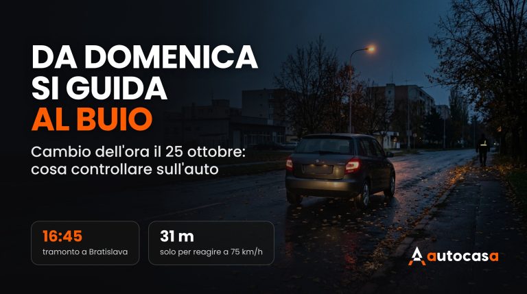 Sera d'autunno in città, auto con le luci accese su asfalto bagnato coperto di foglie e un pedone con banda riflettente sul margine della strada